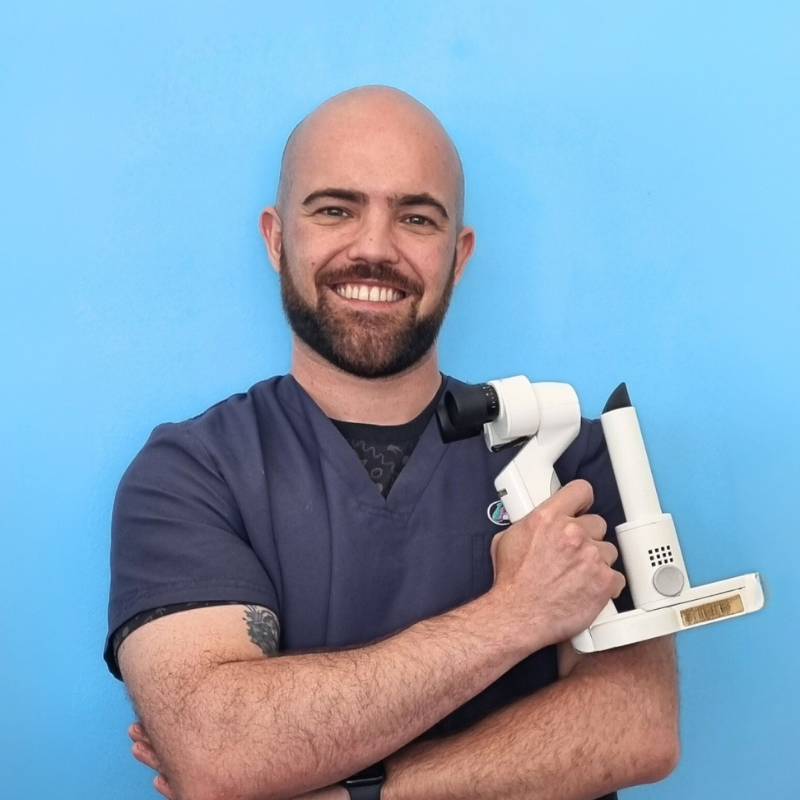 Il Dottor Filippo Maria Pastore, medico veterinario della Clinica Veterinaria Costa d'Argento. Un uomo sorridente in camice medico si staglia su uno sfondo blu, tenendo uno strumento oftalmico con le braccia incrociate sul petto.