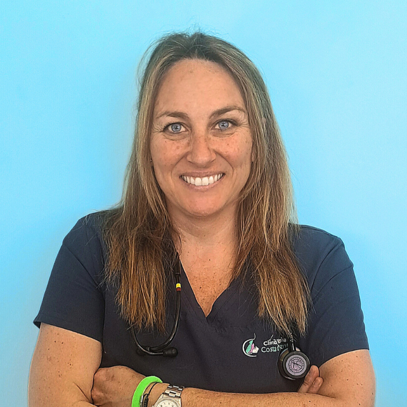 La dottoressa Beatrice Darini, medico veterinario della Clinica Veterinaria Costa d'Argento. Una donna con lunghi capelli castano chiaro sorride alla telecamera, su uno sfondo azzurro. Indossa un'uniforme medica blu navy, uno stetoscopio al collo e un braccialetto verde. Le braccia sono incrociate.