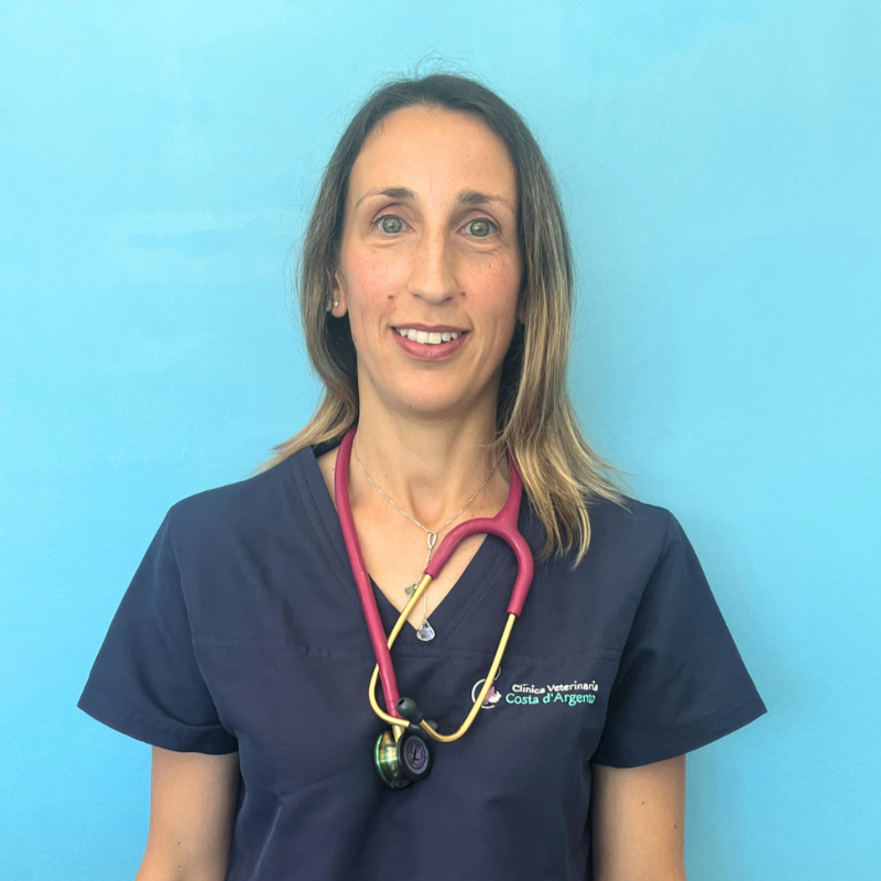 La Dottoressa Palma Vitagliano, medico veterinario della Clinica Veterinaria Costa d'Argento. Una donna con un camice da medico blu scuro e uno stetoscopio rosa al collo si staglia su uno sfondo blu chiaro, sorridendo alla telecamera.